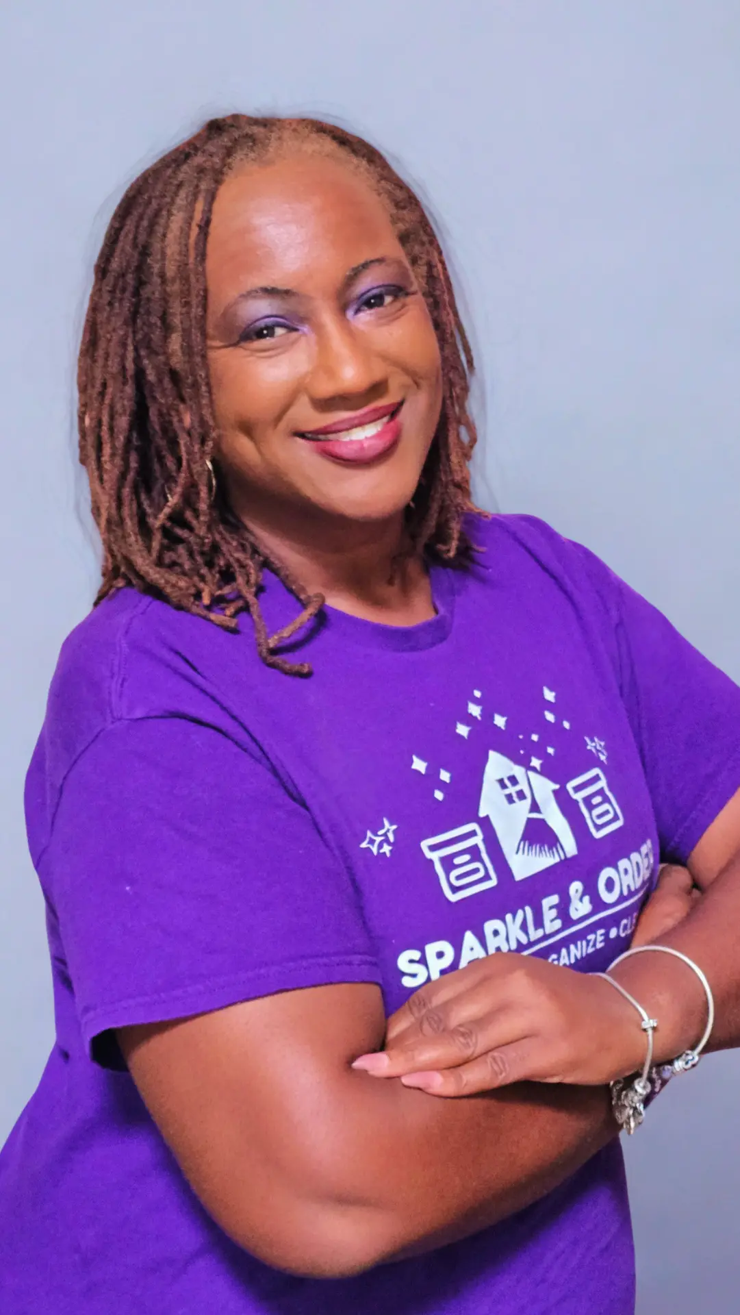 Melinda Riddick, founder and CEO of Sparkle and Order LLC, smiling in a purple company t-shirt